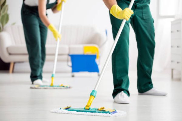 Cleaning team wiping the floor using mops in the flat